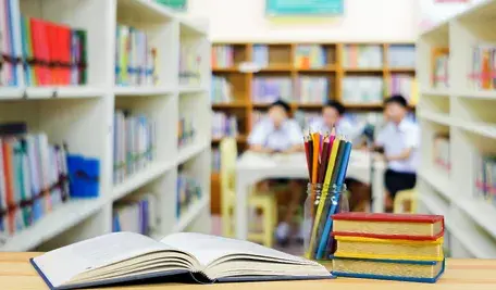 Widok na klase szkolna, na pierwszym planie przybory szkolne