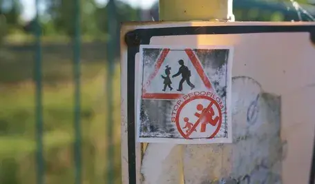 Sticker na słupie z napisem „Stop pedofilom” w przestrzeni publicznej – wyraz społecznego sprzeciwu wobec przemocy seksualnej wobec dzieci, zdjęcie wykonane w naturalnym świetle przy ogrodzeniu, Polska.