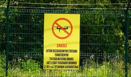 Tablica z napisem „Zakaz lotów bezzałogowymi statkami powietrznymi” na ogrodzeniu wojskowego terenu w Polsce. Zakaz używania dronów w rejonie ćwiczeń NATO i incydentów z niezidentyfikowanymi urządzeniami.