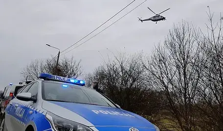 Policyjny radiowóz i helikopter podczas akcji poszukiwawczej w Małopolsce – działania policji po odkryciu trzech ciał w miejscowości Barcice Górne.