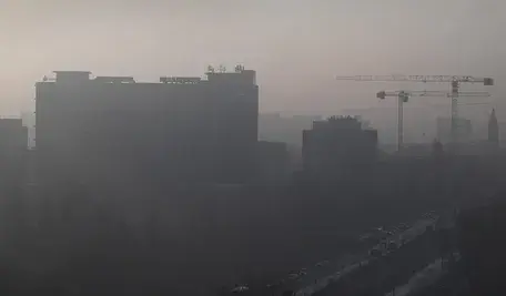 Miasto spowite gęstym smogiem – ograniczona widoczność, zanieczyszczone powietrze unoszące się nad zabudowaniami w dolinie.