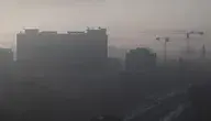 Miasto spowite gęstym smogiem – ograniczona widoczność, zanieczyszczone powietrze unoszące się nad zabudowaniami w dolinie.