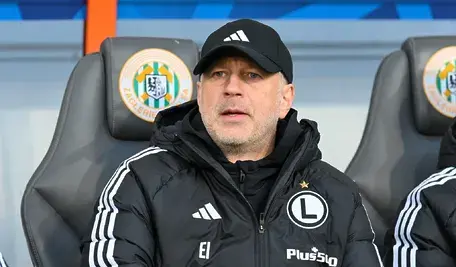 Edward Iordanescu podczas meczu w barwach Legii Warszawa. Rumuński trener, który po serii nieudanych występów podał się do dymisji, widoczny w skupieniu, z poważnym wyrazem twarzy.