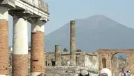 Ruiny starożytnego miasta Pompeje we Włoszech – widok na zachowane fragmenty budowli, brukowaną ulicę i pozostałości amfiteatru na tle Wezuwiusza.