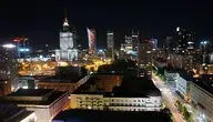 Panorama Warszawy nocą z podświetlonymi wieżowcami i charakterystyczną architekturą śródmieścia, widok na centrum stolicy Polski oświetlone światłami miasta