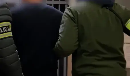 Policjanci prowadzą zatrzymanych mężczyzn podejrzanych o napad na dom 90-letniego przedsiębiorcy w Bytomiu; akcja funkcjonariuszy w dzielnicy Łagiewniki, odzyskano część łupu o wartości 2 mln zł.