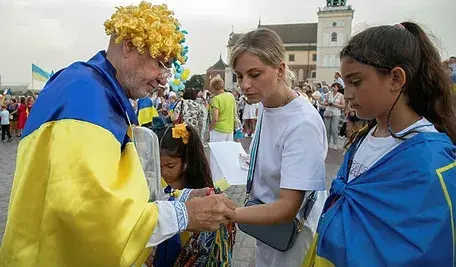 Grupa osób owiniętych ukraińskimi flagami podczas publicznego wydarzenia.