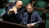 „Jakub Rutnicki i Sławomir Nitras siedzą w ławach parlamentu, rozmawiają ze sobą podczas obrad.