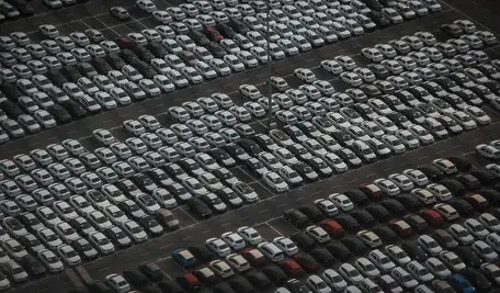 Linia samochodów zaparkowanych pod zakładem produkcyjnym.