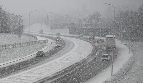 Zasypana śniegiem ulica na Podkarpaciu, ciężkie gałęzie pochylone pod naporem śniegu i pracujące służby usuwające skutki zimowego ataku.