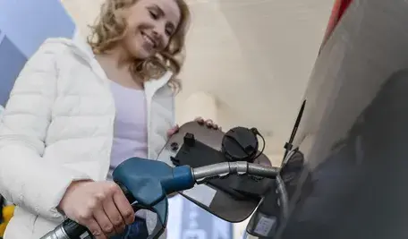 Kobieta w białej kurtce tankuje paliwo na stacji Orlenu. Firma przyznaje, że pomyłka była incydentalna i wynikała z błędu zewnętrznego dostawcy. Rzecznik prasowy Orlen zachęca do zgłaszania wszelkich szkód i podkreśla, że stacja już podjęła działania naprawcze, aby zapobiec powtórzeniu się sytuacji.