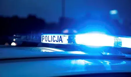 Radiowóz policyjny z włączonymi światłami podczas nocnego patrolu.