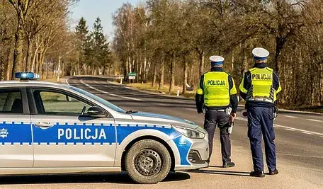 Dwaj policjanci w mundurach podczas kontroli drogowej.