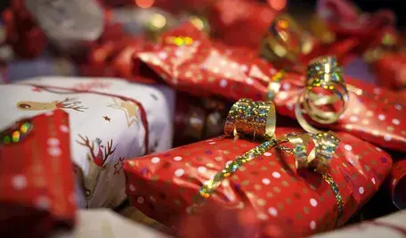 Zapakowane prezenty świąteczne w czerwony i biały papier ozdobny z kolorowymi wstążkami, ułożone obok siebie w bożonarodzeniowej atmosferze.