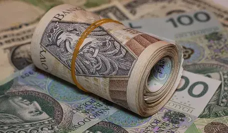 Zwitek polskich banknotów związanych gumką leżący na tle innych banknotów