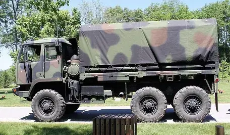 Wojskowa ciężarówka stojąca na drodze w słoneczny dzień.