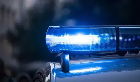 Radiowóz policyjny z włączoną sygnalizacją świetlną.