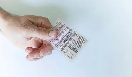 Zbliżenie na dłoń trzymającą plastikowe prawo jazdy.