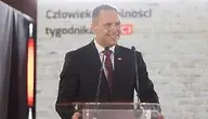 Prezydent Karol Nawrocki przy mównicy podczas wystąpienia publicznego na tle białej ściany.