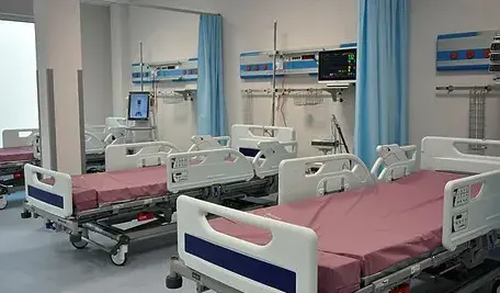 Sala szpitalna z kilkoma łóżkami i aparaturą medyczną bez pacjentów