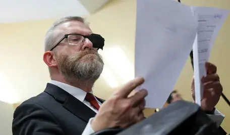 Grzegorz Braun podczas procesu dotyczącego jego akcji z gaśnicą w Sejmie, stojący przed sądem w trakcie rozprawy.