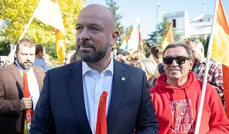 Prezydent Wrocławia, Jacek Sutryk trzyma w rękach flagę, podczas publicznego wydarzenia