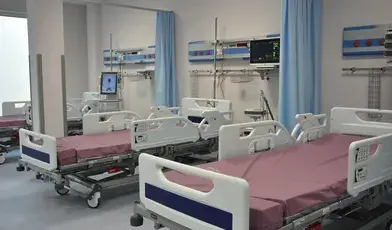 Pusta sala szpitalna z kilkoma łóżkami, szafkami nocnymi i zasłoniętymi oknami. Zdjęcie ilustruje zawieszenie Oddziału Chirurgii Ogólnej w szpitalu w Nakle nad Notecią z powodu braku lekarzy specjalistów.