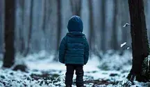 Dziecko w zimowej kurtce stojące samotnie w zaśnieżonym lesie.