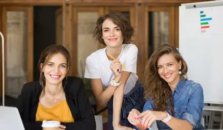 Uśmiechnięte młode kobiety na tle tablicy