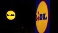 Logo sieci Lidl na elewacji sklepu nocą, podświetlony szyld widoczny na ciemnym tle.