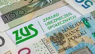Kartka z logo Zakładu Ubezpieczeń Społecznych przykryta banknotami.