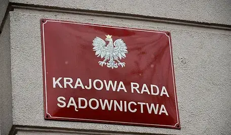 Czerwona tablica informacyjna przy wejściu do budynku Krajowej Rady Sądownictwa.