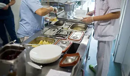 Kucharki nakładające jedzenie w szpitalu.