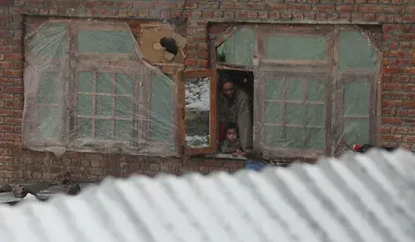 Hinduska rodzina w północnej części kraju siedzi w domu i patrzy na śnieg