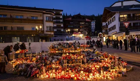 Kwiaty i zapalone świece tworzą wzruszający hołd dla ofiar tragicznego pożaru w barze Le Constellation w Crans-Montana, Szwajcaria, 4 stycznia 2026 r. Katastrofa sylwestrowa pochłonęła 40 ofiar śmiertelnych i raniła ponad 100 osób w alpejskim kurorcie. EPA/JEAN-CHRISTOPHE BOTT.
