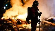 A French firefighter responds to a street barricade burns as clashes between riot police and demonstrators continue for the second day during nationwide protests against the high cost of living in Paris, France, 18 October 2026.