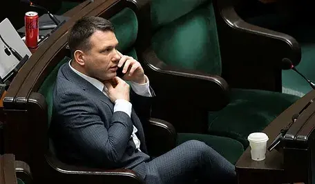 Sławomir Mentzen rozmawiający przez telefon na sali sejmowej