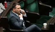 Sławomir Mentzen rozmawiający przez telefon na sali sejmowej