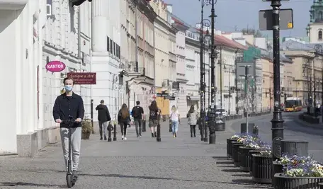 Młodzieniec na hulajnodze jedzie chodnikiem