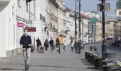 Młodzieniec na hulajnodze jedzie chodnikiem 