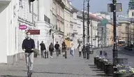 Młodzieniec na hulajnodze jedzie chodnikiem 