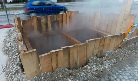 Dziura w jezdni zabezpieczona drewnianym ogrodzeniem