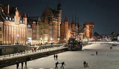 Ludzie chodzący nocą po zamarzniętej rzece.