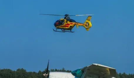 Żółty śmigłowiec Lotniczego Pogotowia Ratunkowego na tle błękitnego nieba.