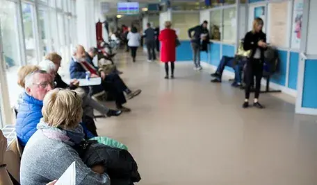 Pacjenci czekający w kolejce przed gabinetem lekarskim.