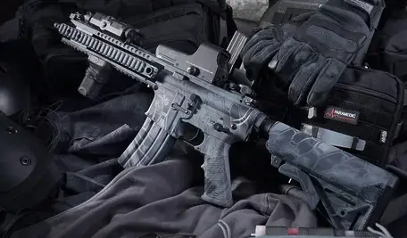 Karabin ułożony na czarnej odzieży.