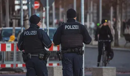 Dwóch umundurowanych funkcjonariuszy niemieckiej policji podczas patrolowania ulicy.
