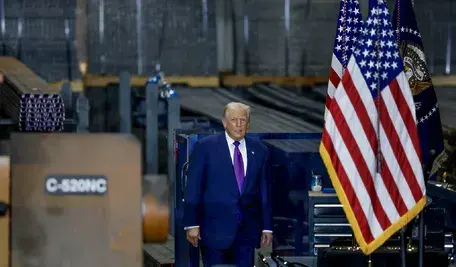 Prezydent USA Donald Trump obok flagi Stanów Zjednoczonych.