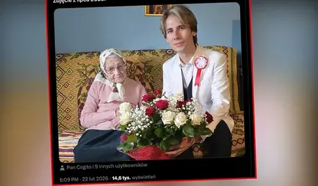 Portret najstarszej Polki, pani Anny Winiarskiej, siedzącej na kanapie obok Wacława Jana Kroczka z Gerontology Research Group. Pani Anna, ubrana w różowy sweter i kwiecistą chustę, trzyma duży bukiet czerwonych i białych róż. Mężczyzna w białej marynarce z pamiątkową przypinką uśmiecha się do obiektywu.