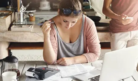 Młoda kobieta zmartwiona nad laptopem. 